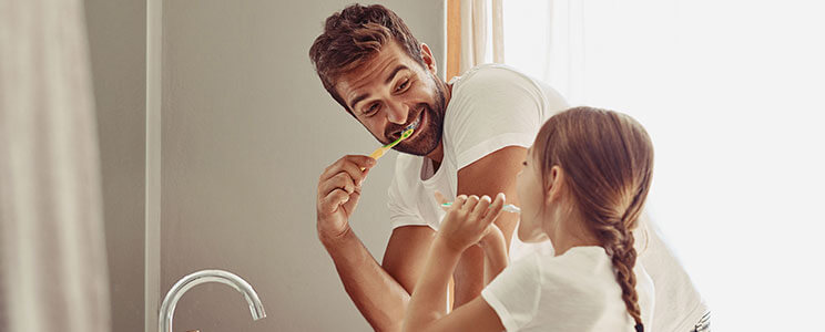 father and daughter brushing teeth in the bathroom