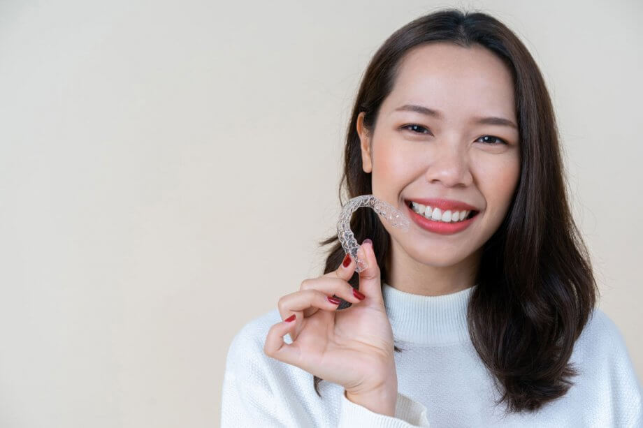 young woman holding dental aligner